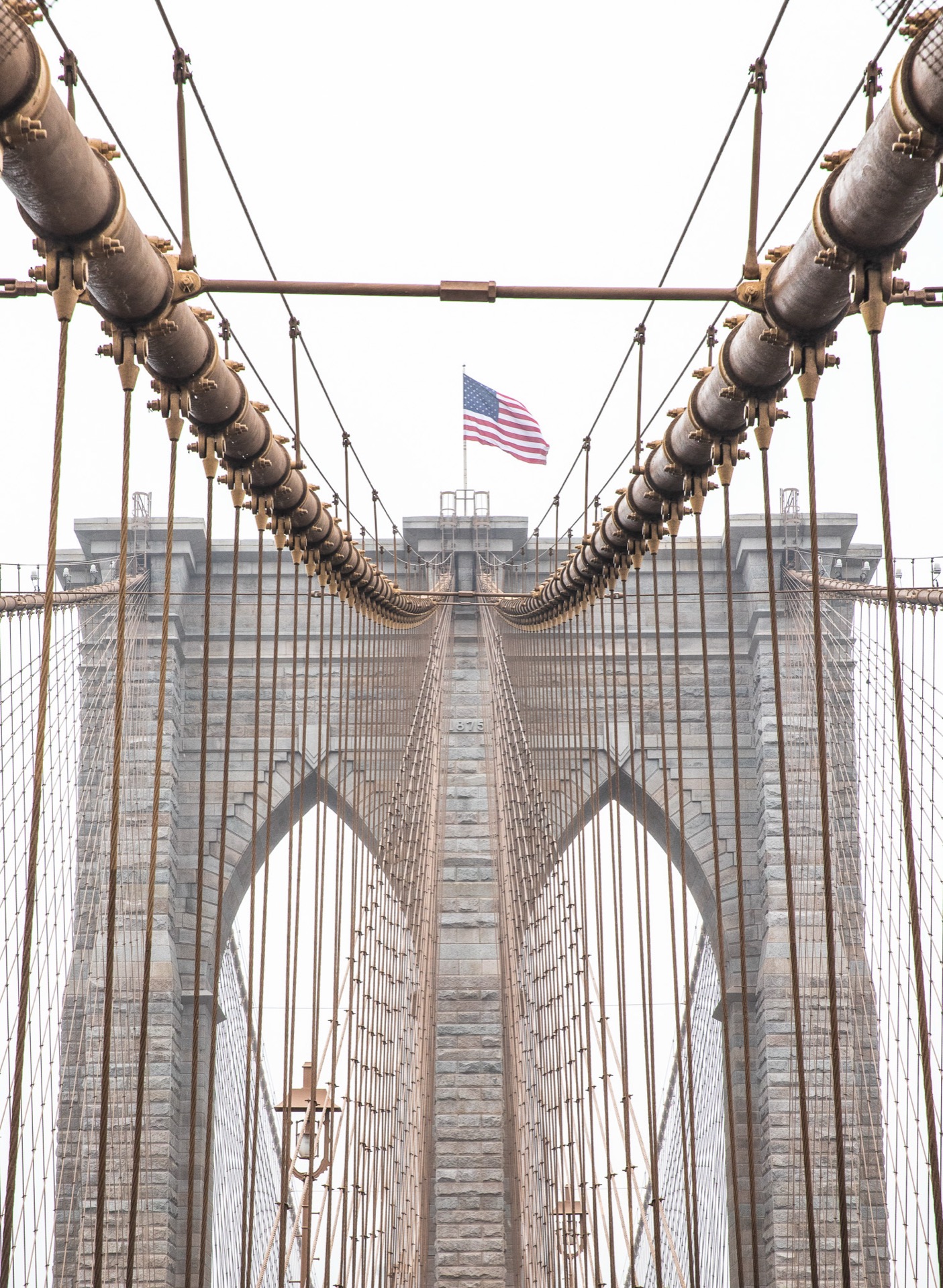 Brooklyn Bridge towers seen through cables with American flag, New York